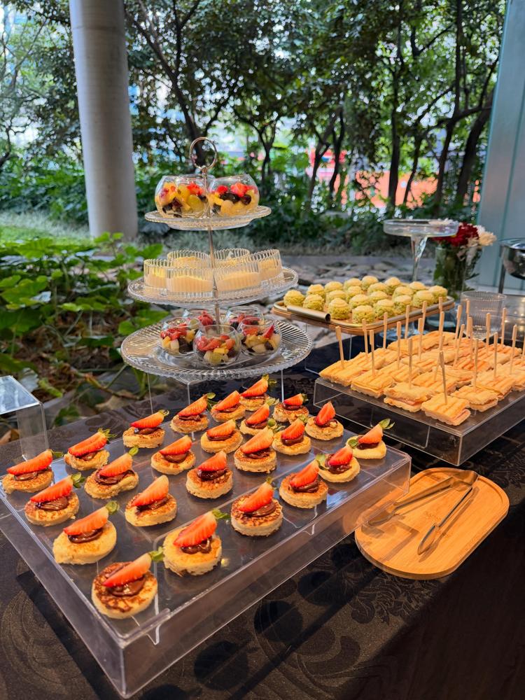Mesa de finger foods em suportes de acrílico com folhagens