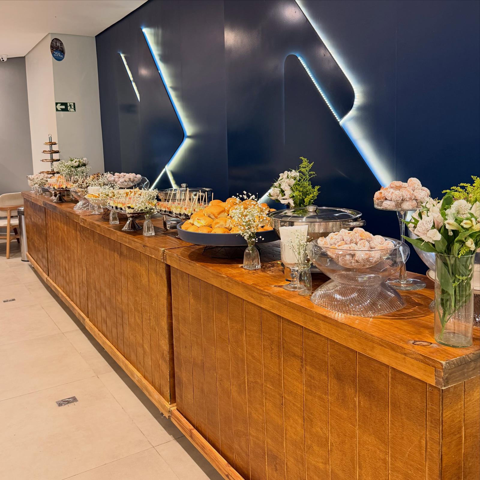 Balcão de madeira com buffet completo e arranjos de flores