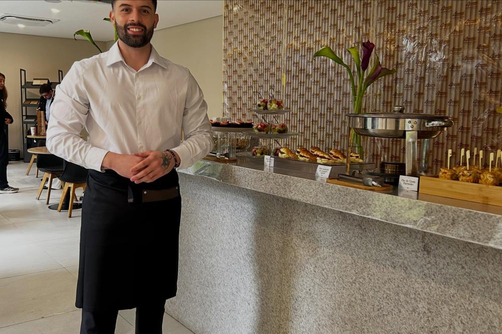 Garçom da S23 ao lado do buffet montado